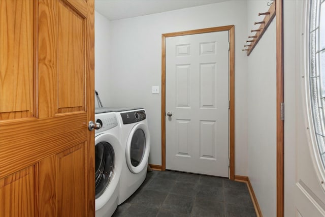 clothes washing area with baseboards, laundry area, and washer and clothes dryer