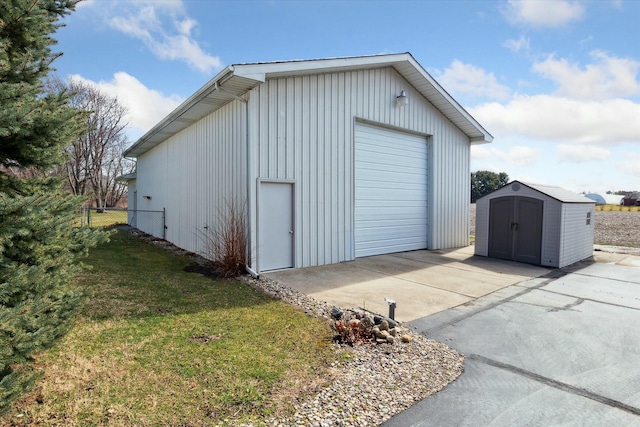 detached garage featuring concrete driveway and fence