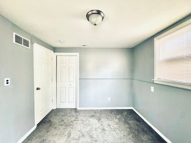 interior space with baseboards, wainscoting, visible vents, and carpet floors