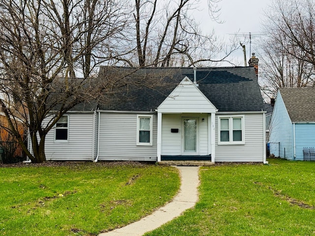 view of front of property featuring a front yard, a shingled roof, and a chimney