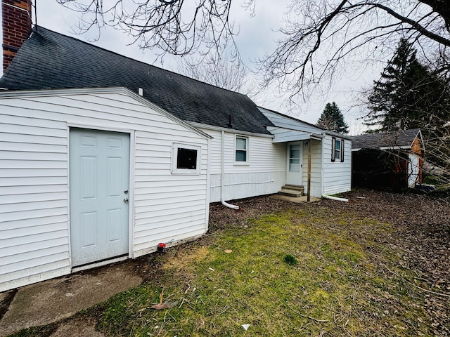 rear view of house featuring entry steps and a shingled roof