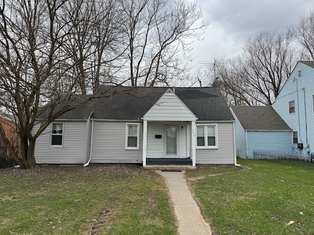 view of front of house with a front yard and a shingled roof