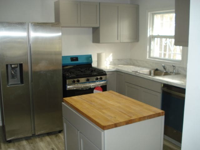 20885 Westview Ave, Ferndale, MI 48220 - kitchen with stainless steel appliances, a center island, light wood-style flooring, a sink, and butcher block counters