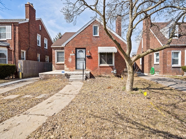 bungalow-style home featuring brick siding, a chimney, and fence