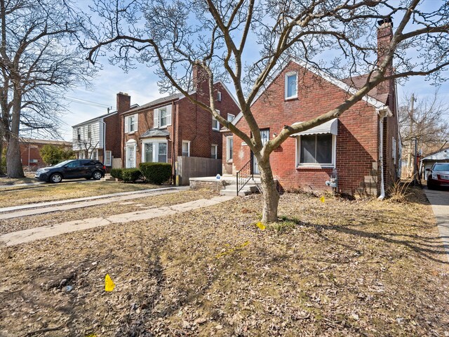 view of front of house with brick siding, a residential view, and a chimney