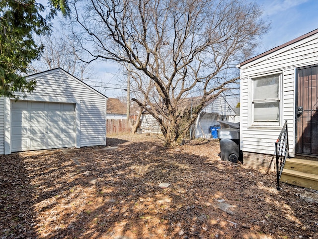 view of yard featuring entry steps, an outdoor structure, fence, and a garage