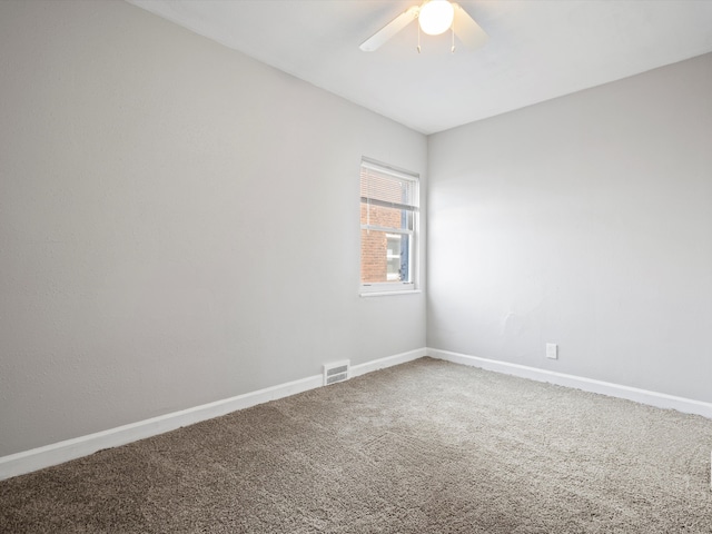 carpeted empty room with visible vents, baseboards, and ceiling fan