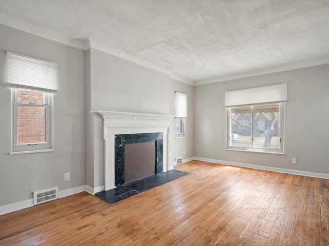 unfurnished living room with plenty of natural light, visible vents, and wood-type flooring