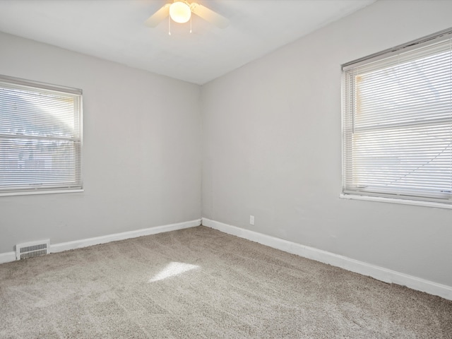 unfurnished room featuring carpet flooring, visible vents, baseboards, and a ceiling fan