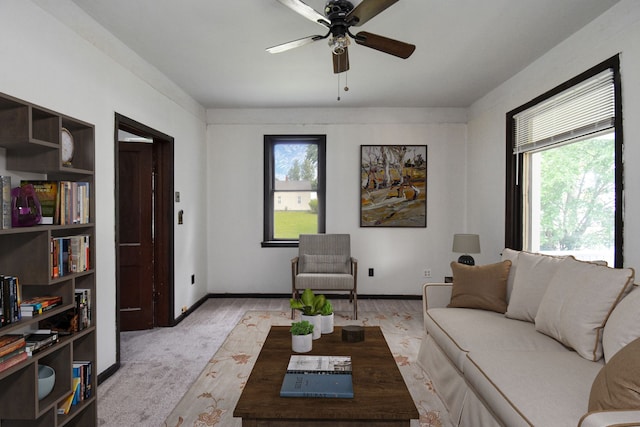 living room featuring plenty of natural light, a ceiling fan, baseboards, and light carpet