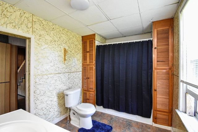 bathroom featuring wallpapered walls, toilet, a shower with shower curtain, a closet, and a paneled ceiling