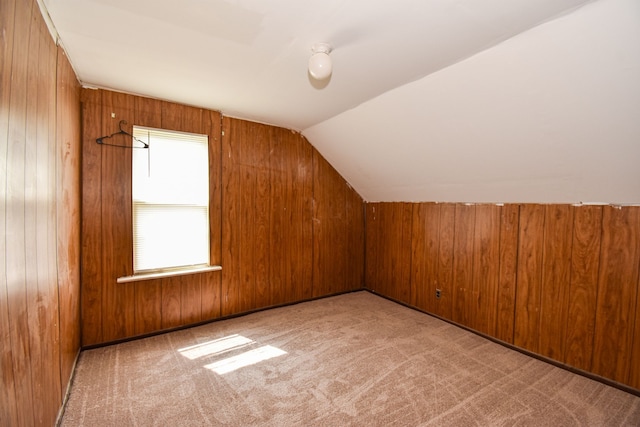 bonus room featuring vaulted ceiling, carpet flooring, and wood walls