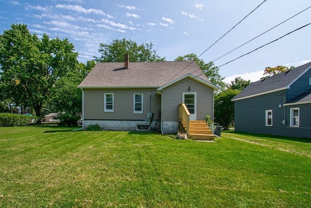 rear view of house with a yard and a shingled roof