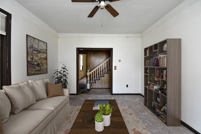 living area featuring stairway, carpet flooring, baseboards, and a ceiling fan