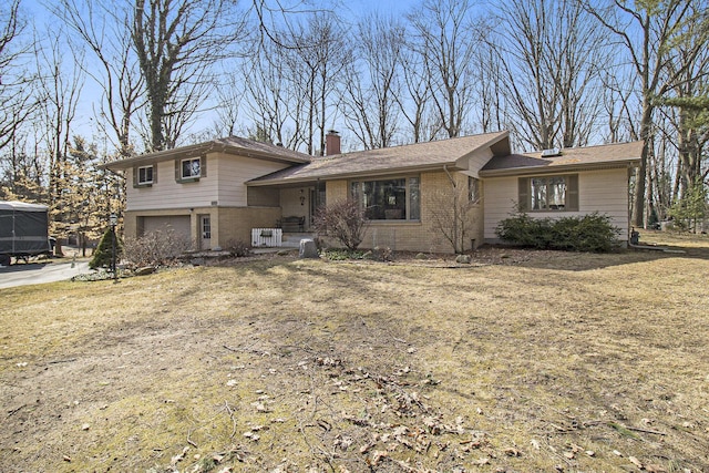 split level home featuring brick siding, an attached garage, and a chimney