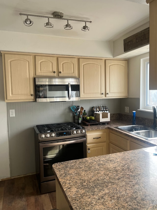 kitchen featuring a sink, dark countertops, appliances with stainless steel finishes, and light brown cabinets