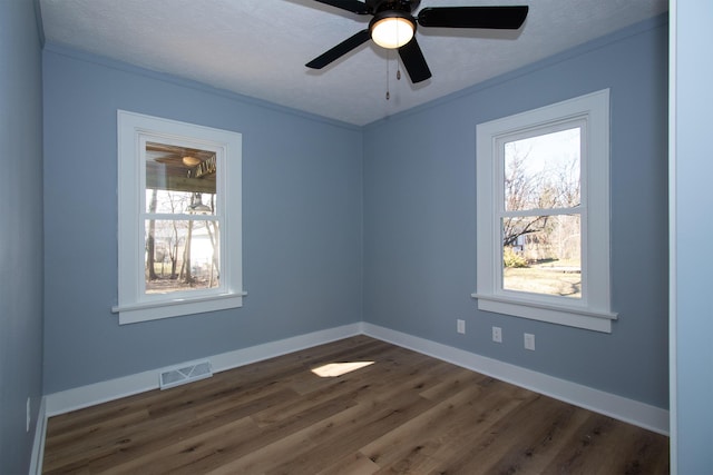 unfurnished room with plenty of natural light, baseboards, visible vents, and dark wood-style flooring