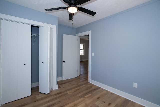 unfurnished bedroom with crown molding, baseboards, wood finished floors, a closet, and a textured ceiling