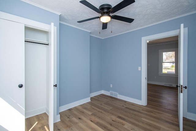 unfurnished bedroom with visible vents, wood finished floors, and ornamental molding