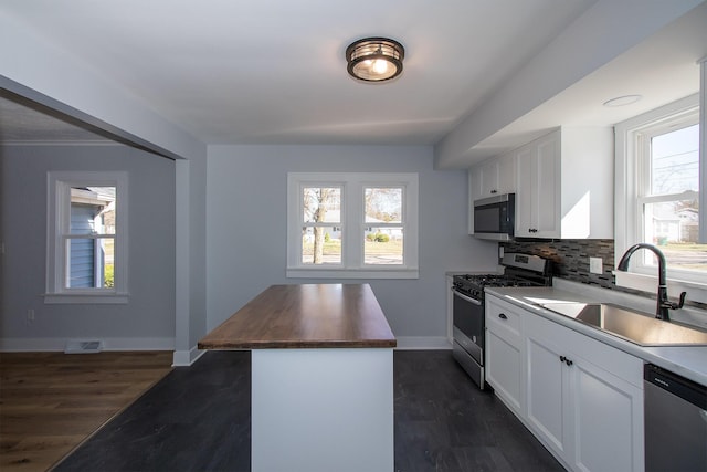 kitchen with visible vents, a sink, wood counters, tasteful backsplash, and appliances with stainless steel finishes