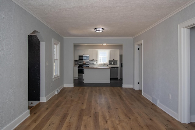 kitchen with visible vents, ornamental molding, backsplash, white cabinetry, and stainless steel appliances