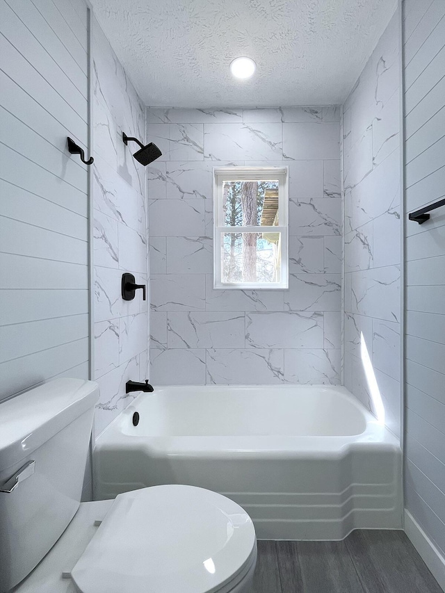 full bathroom featuring a textured ceiling, toilet, shower / tub combination, and wood finished floors