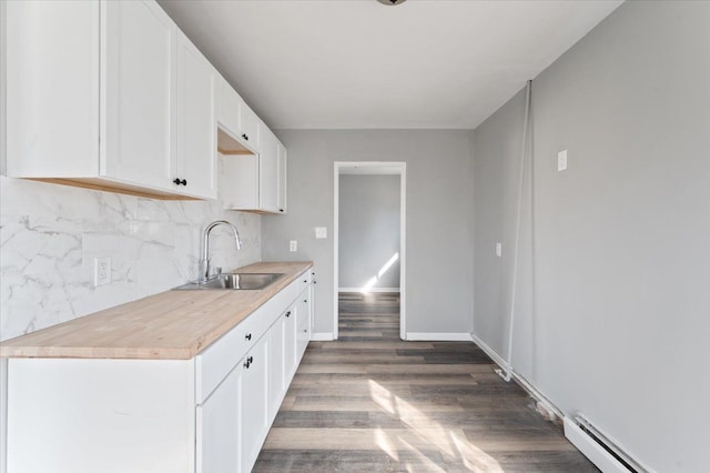 kitchen with a sink, backsplash, white cabinetry, light countertops, and a baseboard radiator