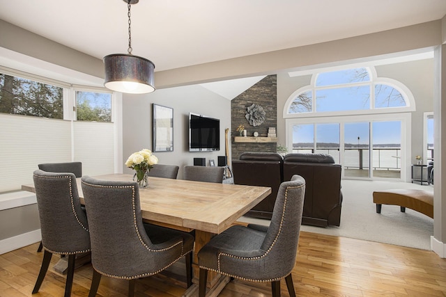 dining space with lofted ceiling, a healthy amount of sunlight, and light wood finished floors