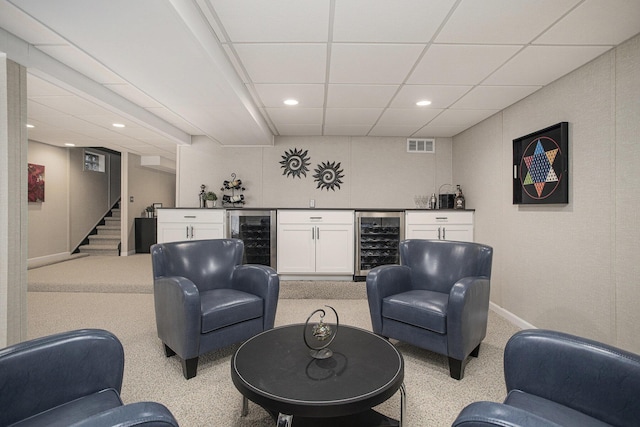 living room with stairway, a paneled ceiling, a bar, and beverage cooler