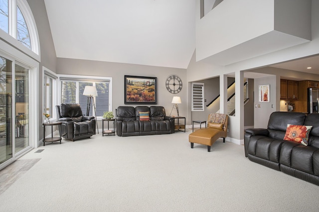 carpeted living room with a high ceiling, stairway, a healthy amount of sunlight, and baseboards