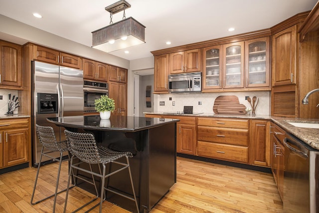 kitchen featuring a breakfast bar, brown cabinets, stainless steel appliances, and a sink