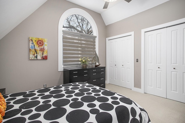 bedroom featuring ceiling fan, vaulted ceiling, two closets, and light carpet