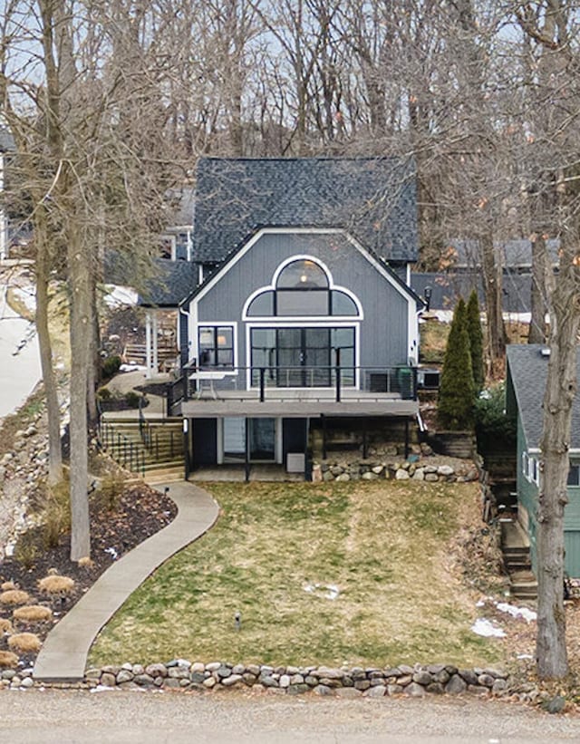 view of front facade with stairway, a wooden deck, and a front lawn