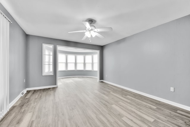 empty room with baseboards, wood finished floors, visible vents, and ceiling fan