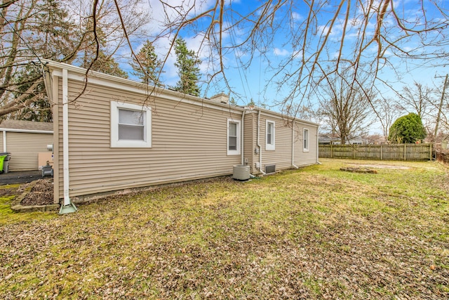 back of house featuring central air condition unit, a lawn, and fence