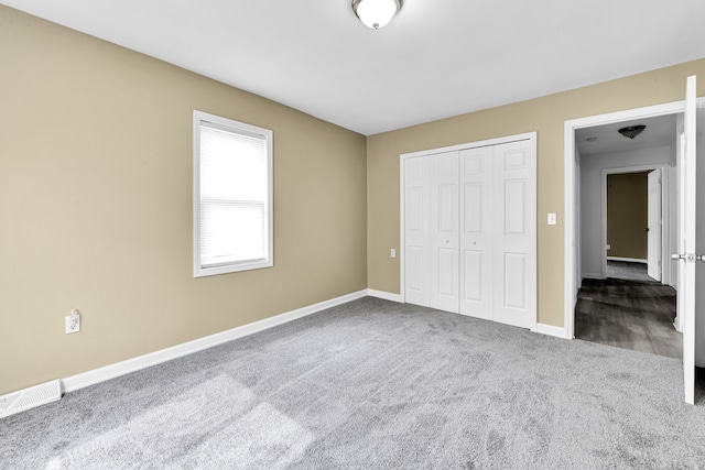unfurnished bedroom with visible vents, baseboards, carpet, and a closet