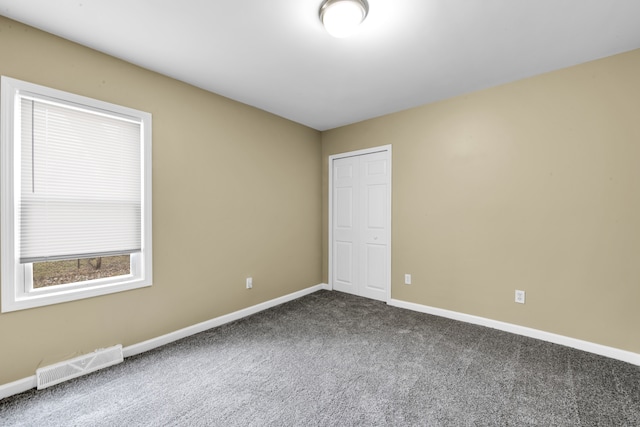 unfurnished room featuring baseboards, visible vents, and dark carpet