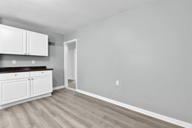 interior space featuring light wood-type flooring, visible vents, and baseboards