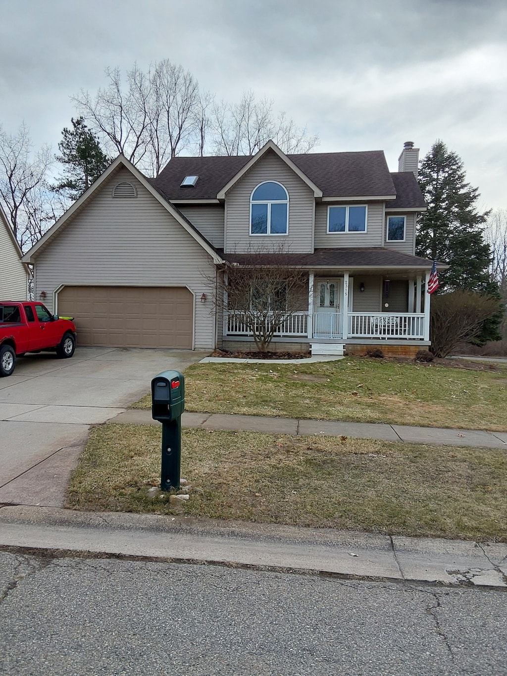2315 Blue Heron, Fenton, MI 48430 - view of front of home with an attached garage, a front lawn, a chimney, covered porch, and driveway