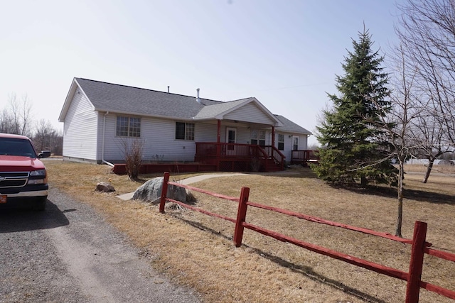 1758 Manor Rd, Au Gres, MI 48703 - ranch-style house featuring gravel driveway, a deck, fence, and roof with shingles