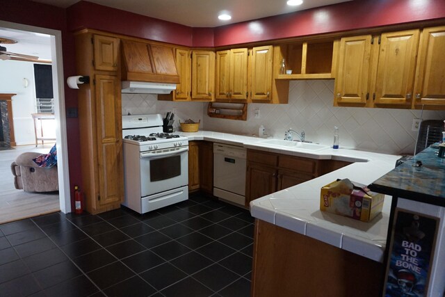 1758 Manor Rd, Au Gres, MI 48703 - kitchen featuring dark tile patterned floors, a sink, under cabinet range hood, white appliances, and tile counters