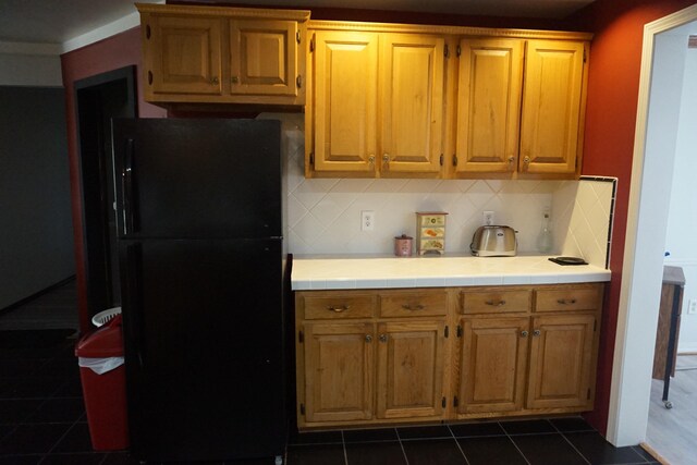 1758 Manor Rd, Au Gres, MI 48703 - kitchen featuring tasteful backsplash, tile counters, dark tile patterned flooring, and freestanding refrigerator