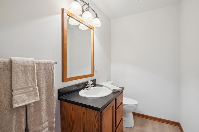 131 E Jolly Rd Unit E6, Lansing, MI 48910 - half bathroom featuring vanity, toilet, baseboards, and wood finished floors