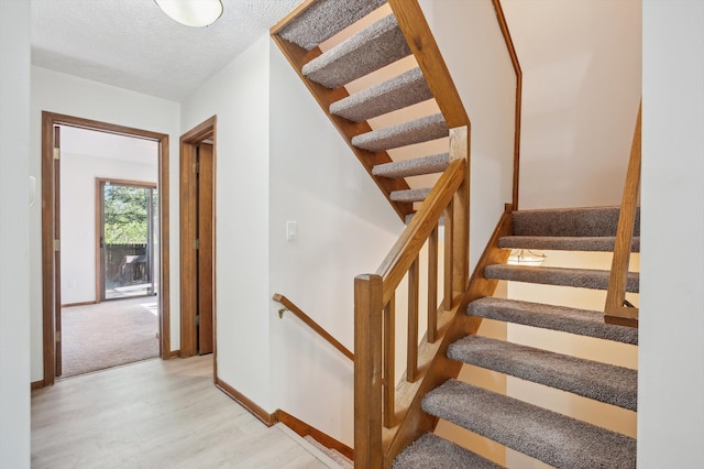 131 E Jolly Rd Unit E6, Lansing, MI 48910 - stairway featuring wood finished floors, baseboards, and a textured ceiling
