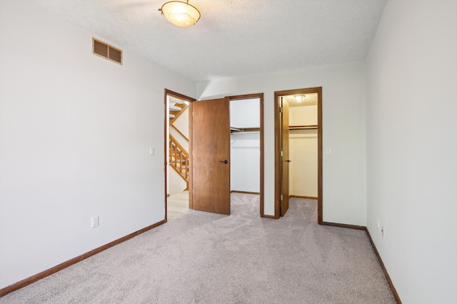 131 E Jolly Rd Unit E6, Lansing, MI 48910 - unfurnished bedroom with carpet floors, baseboards, a walk in closet, a textured ceiling, and a closet