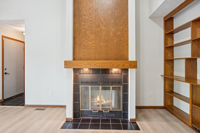 131 E Jolly Rd Unit E6, Lansing, MI 48910 - detailed view of wood finished floors, a tile fireplace, and baseboards