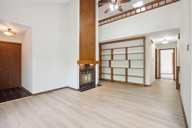 131 E Jolly Rd Unit E6, Lansing, MI 48910 - unfurnished living room featuring wood finished floors, ceiling fan, a fireplace with flush hearth, and baseboards