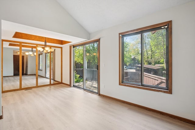 131 E Jolly Rd Unit E6, Lansing, MI 48910 - unfurnished room with a chandelier, light wood-type flooring, baseboards, and lofted ceiling