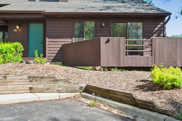 131 E Jolly Rd Unit E6, Lansing, MI 48910 - view of property exterior featuring roof with shingles, a chimney, and fence