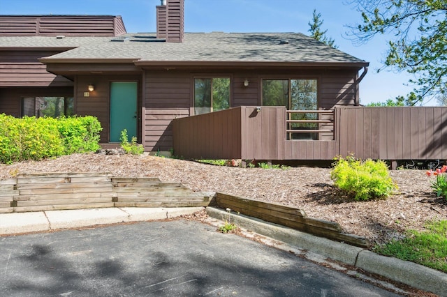 131 E Jolly Rd Unit E6, Lansing, MI 48910 - view of side of home featuring a chimney, a shingled roof, and a patio area
